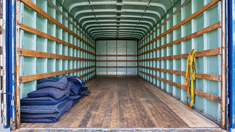 Interior de la caja de un camión con colchonetas y cinchos para asegurar la carga